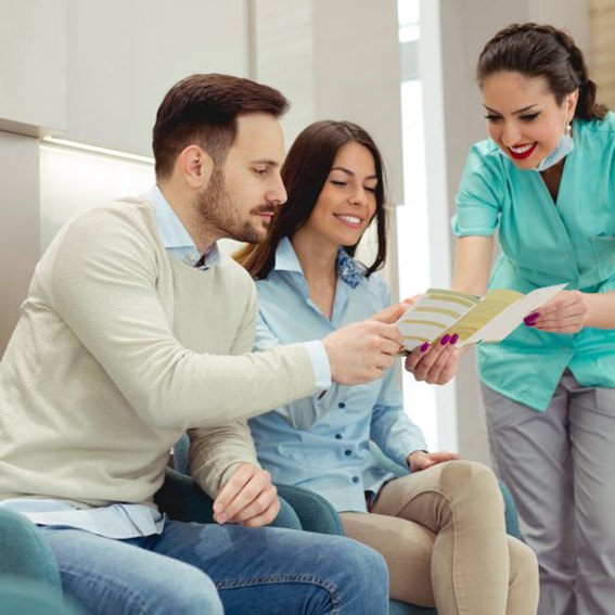 Dental assistant showing a couple information about dental insurance