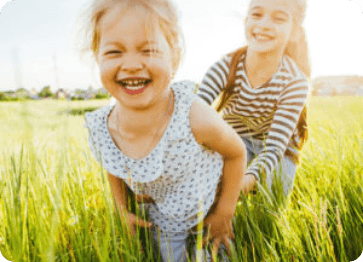 Two laughing girls playing in grassy field