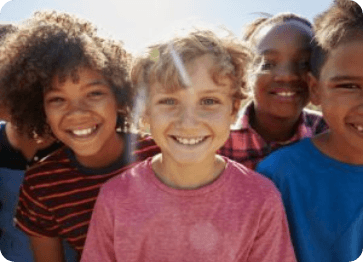 Group of children smiling outdoors on sunny day