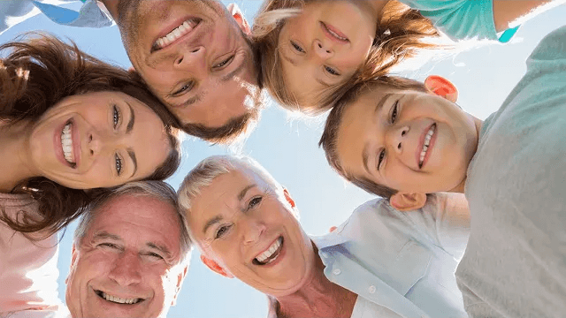 Six smiling family members putting their heads together in circle formation