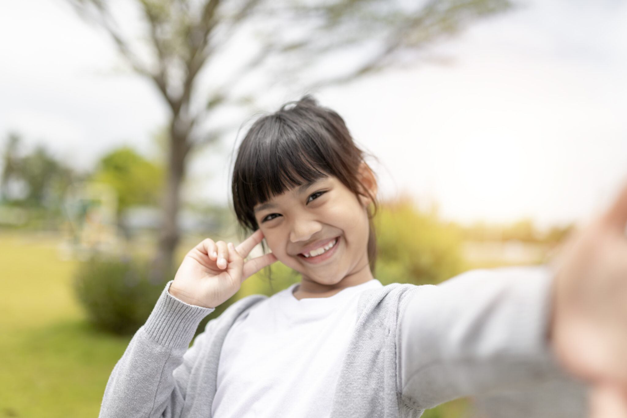 Young girl taking selfie outdoors after children's restorative dentistry in East Cobb