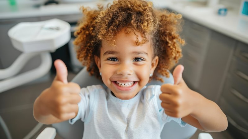 little girl giving thumbs up in the treatment chair