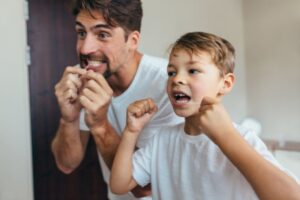 Father teaching son to floss.