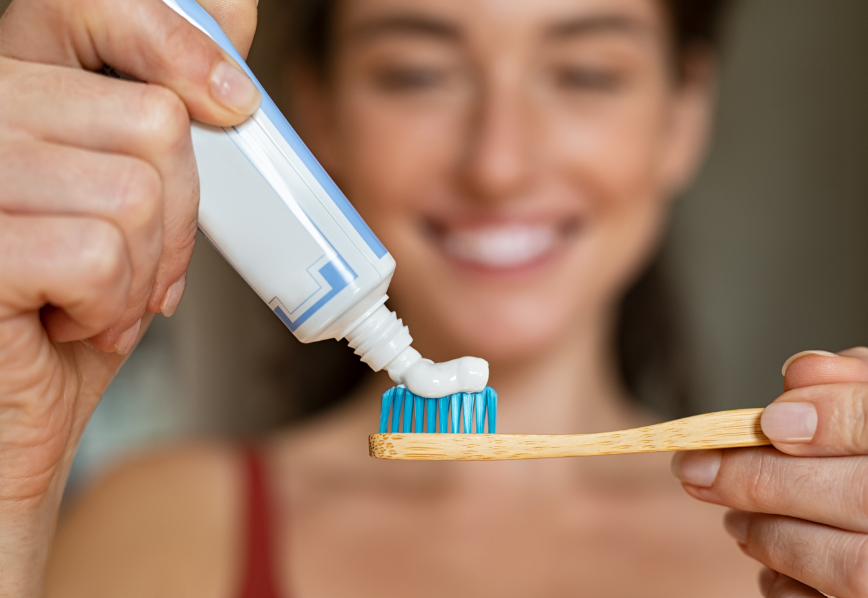 Woman putting toothpaste on toothbrush.